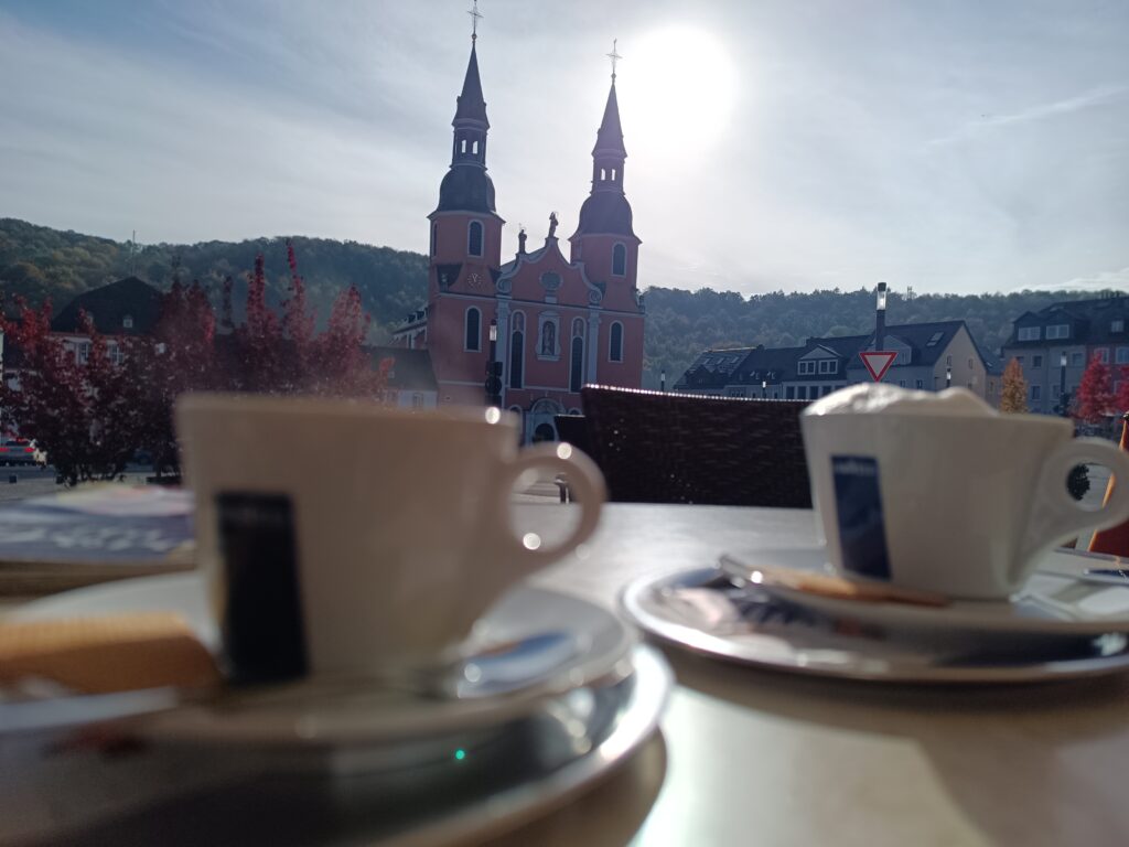 Basilika im Hintergrund mit Kaffeetassen im Vordergrund, ruhige Szene auf der Via Coloniensis