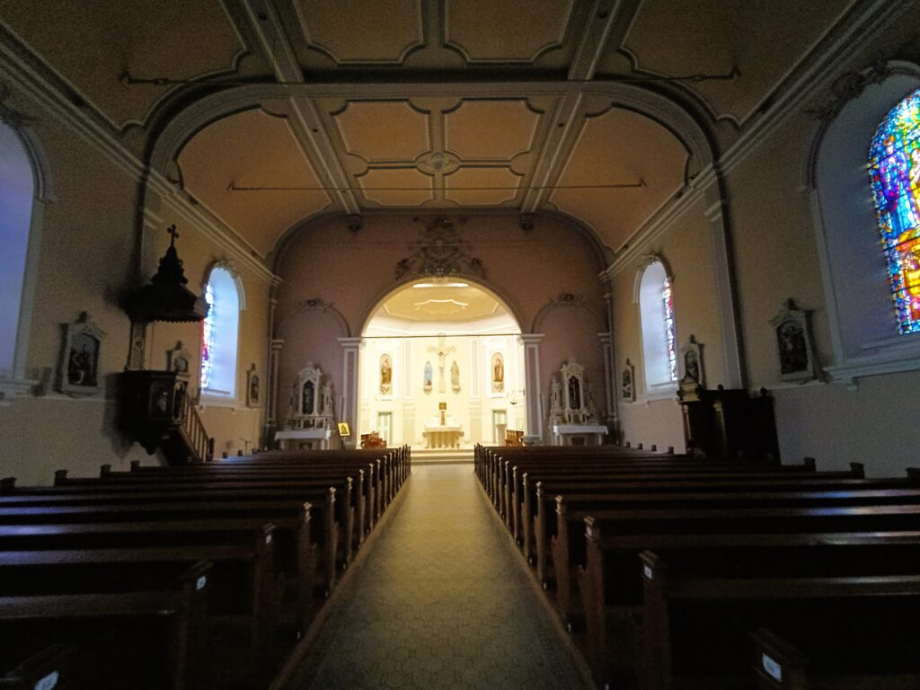 Innenraum der Église St Rémy mit Bankreihen und zentralem Altar.