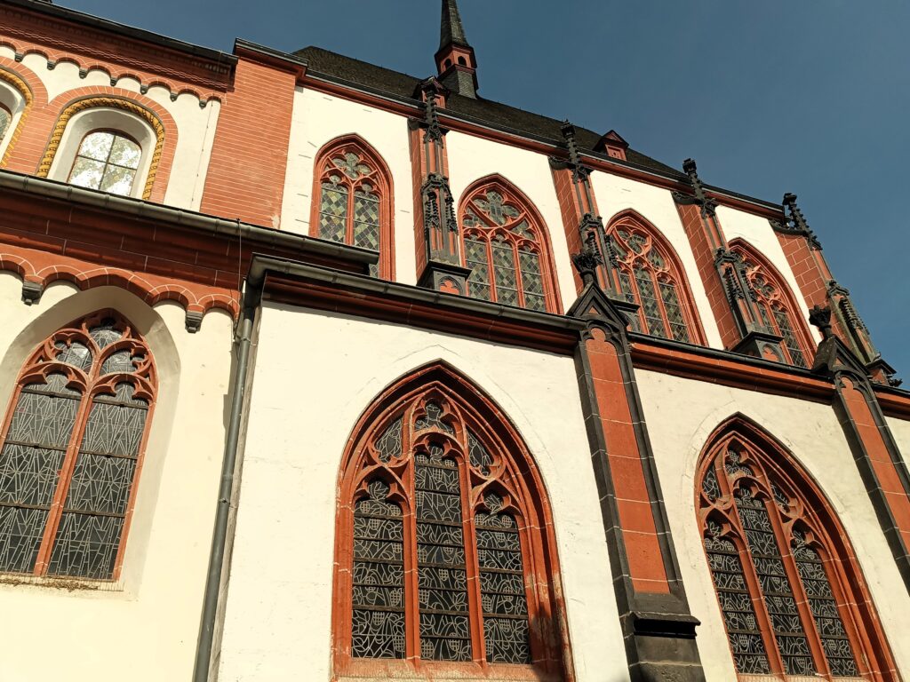 Außenansicht des Langschiffs der Liebfrauenkirche in Koblenz mit gotischen Maßwerkfenstern.