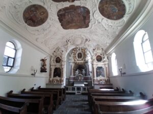 Innenansicht der Michaelskapelle mit barockem Dekor, Altar und Bankreihen.