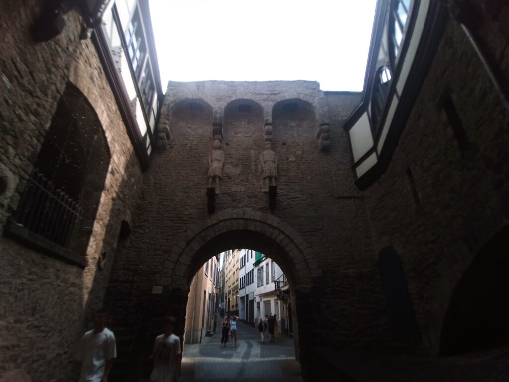 Innenseite des Rheintors in Andernach mit den spätromanischen Wächterfiguren und Blick durch den Torbogen.