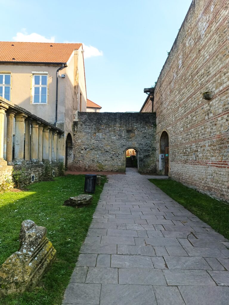 Innenhof der Kirche Saint-Pierre-aux-Nonnains mit romanischen Strukturen und einem Durchgang zur Kirche.