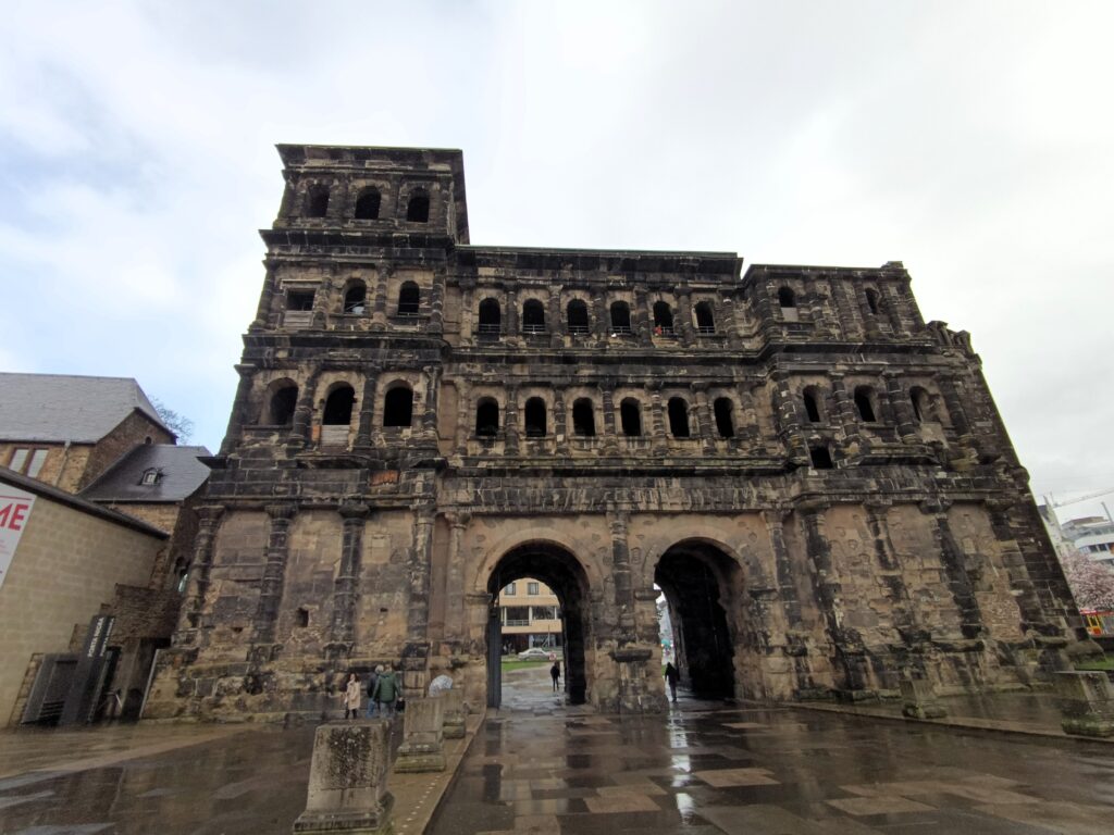 Komplette Frontansicht der Porta Nigra in Trier, aufgenommen bei Tageslicht mit klar erkennbaren Architekturelementen.