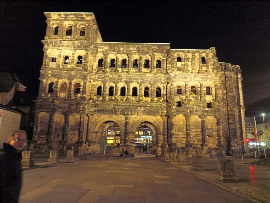 Porta Nigra bei Nacht, frontal beleuchtet mit warmem Licht und erkennbaren Details der römischen Architektur