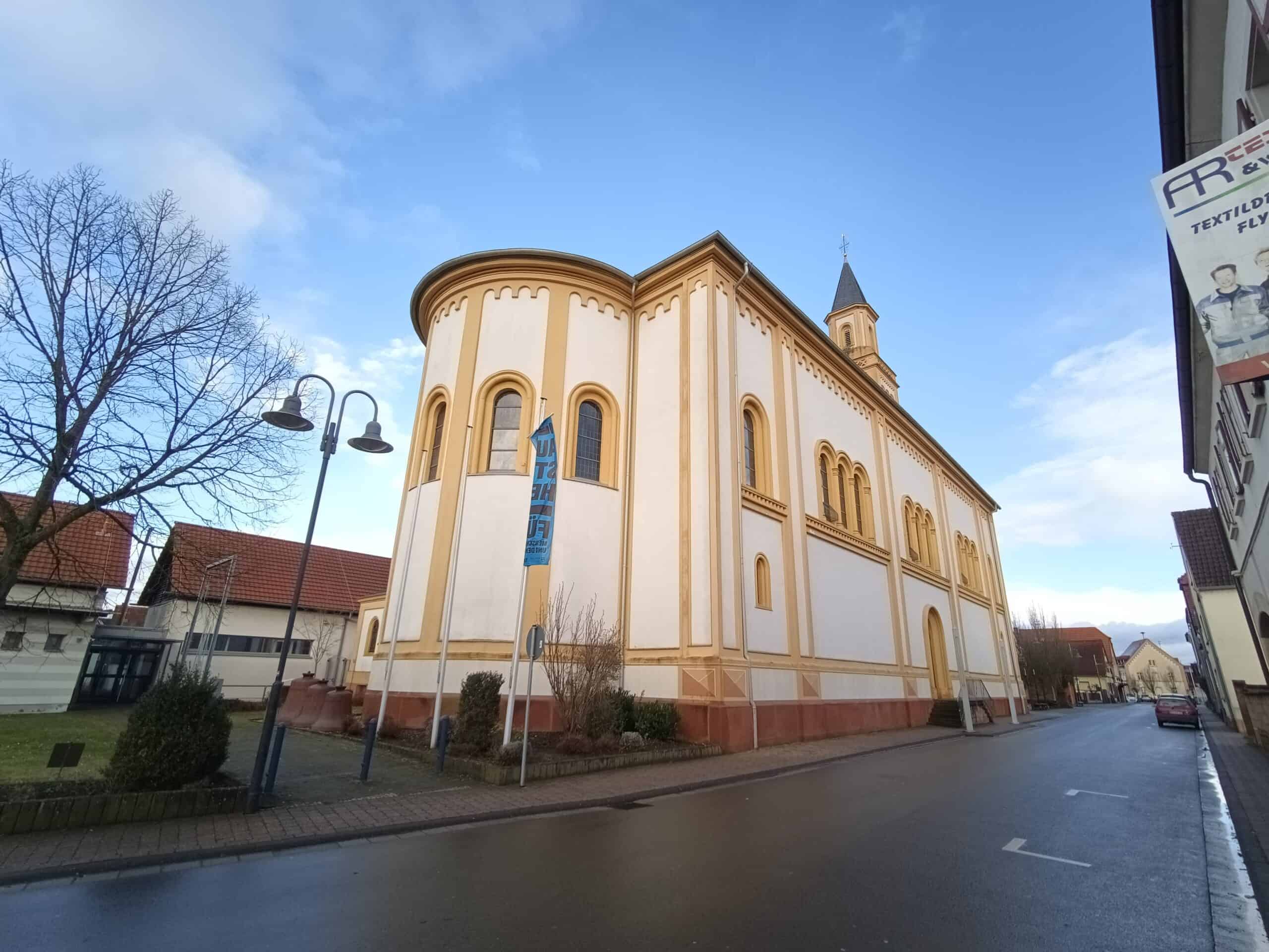 Außenansicht der katholischen Pfarrkirche St. Martin in Lingenfeld, neoromanischer Saalbau mit Rundapsis und Turm.