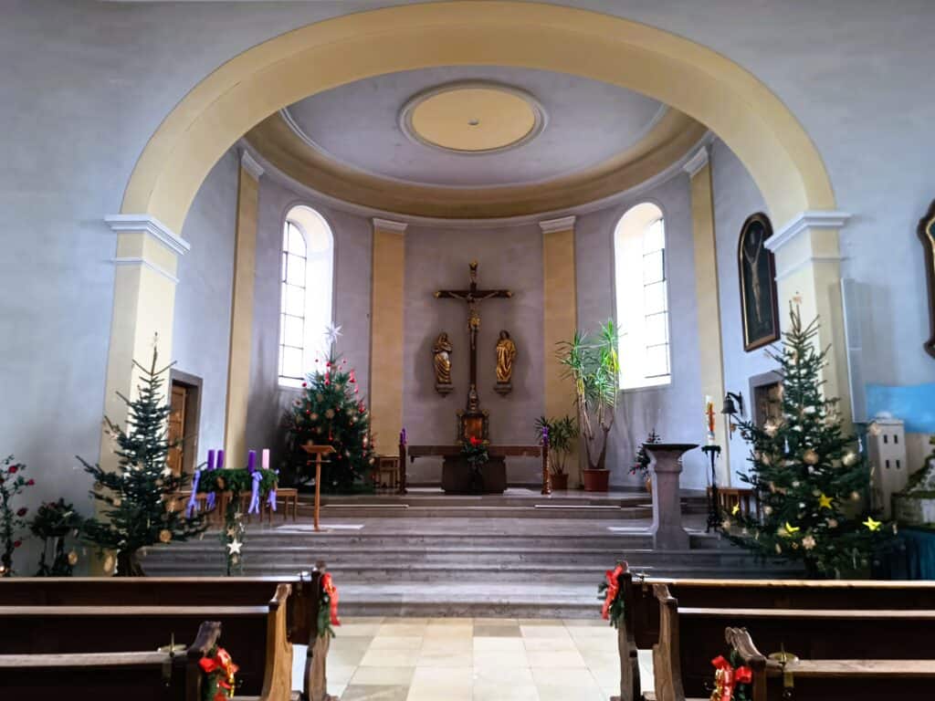 Blick auf den Hochaltarbereich der Pfarrkirche St. Mauritius in Rülzheim mit Kreuz, Heiligenfiguren und festlichem Weihnachtsschmuck.