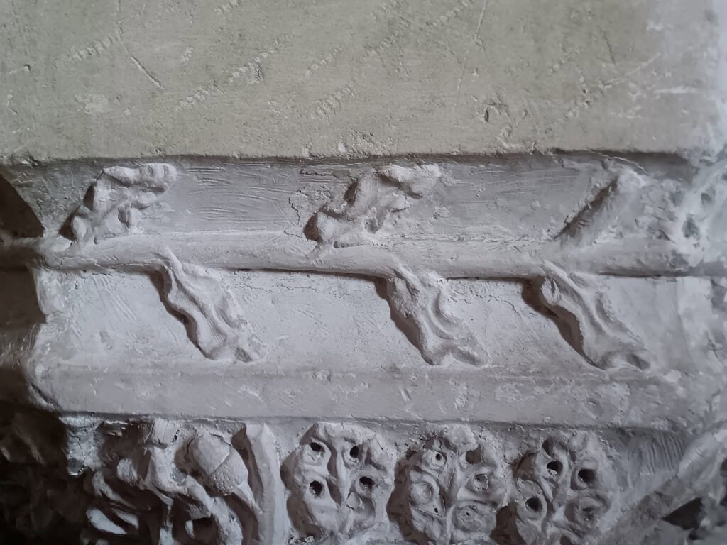 Detailaufnahme des Taufbeckens mit gotischen Arkaden und figürlichen Elementen