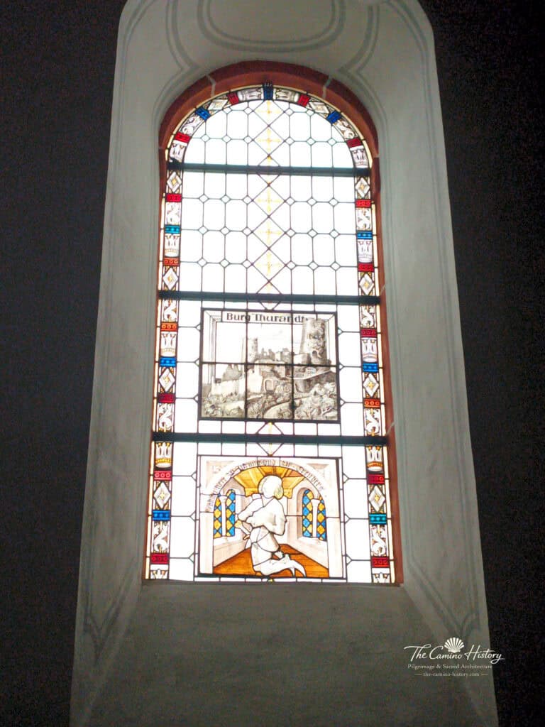 Kirchenfenster in St. Luzia Löf mit einer Darstellung eines Ritters in einer Kapelle, im Hintergrund die Burg Thurant. Restauriert 1991.