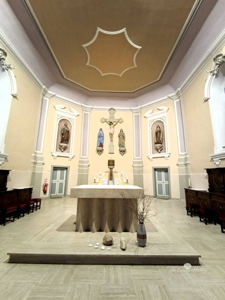 Die schlichte Apsis der Église St Rémy mit zentralem Kruzifix und Heiligenstatuen.