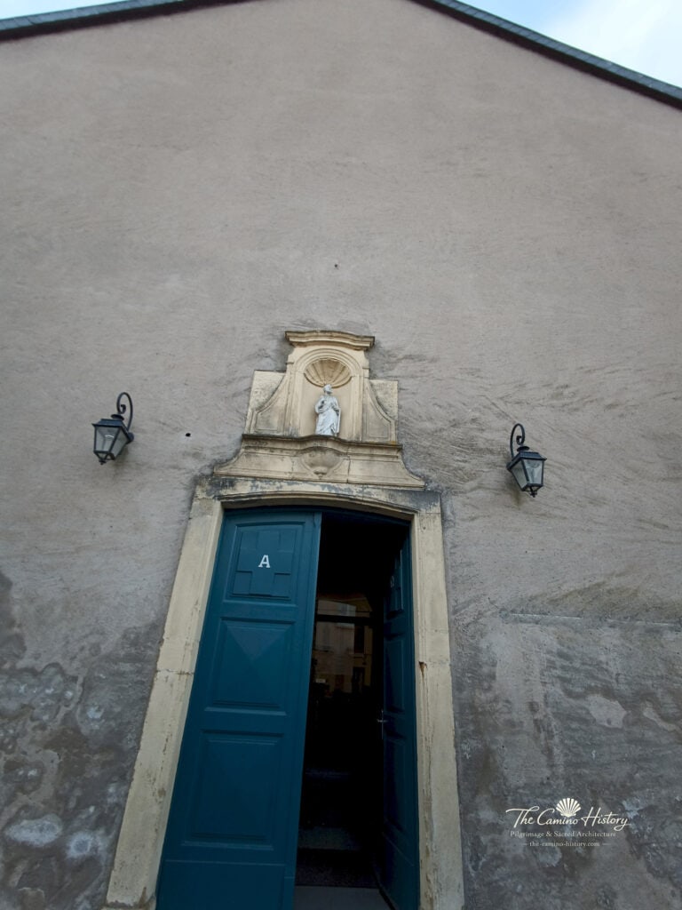 Das Kirchenportal der Église St Rémy mit markanten blauen Türen und Heiligenfigur.