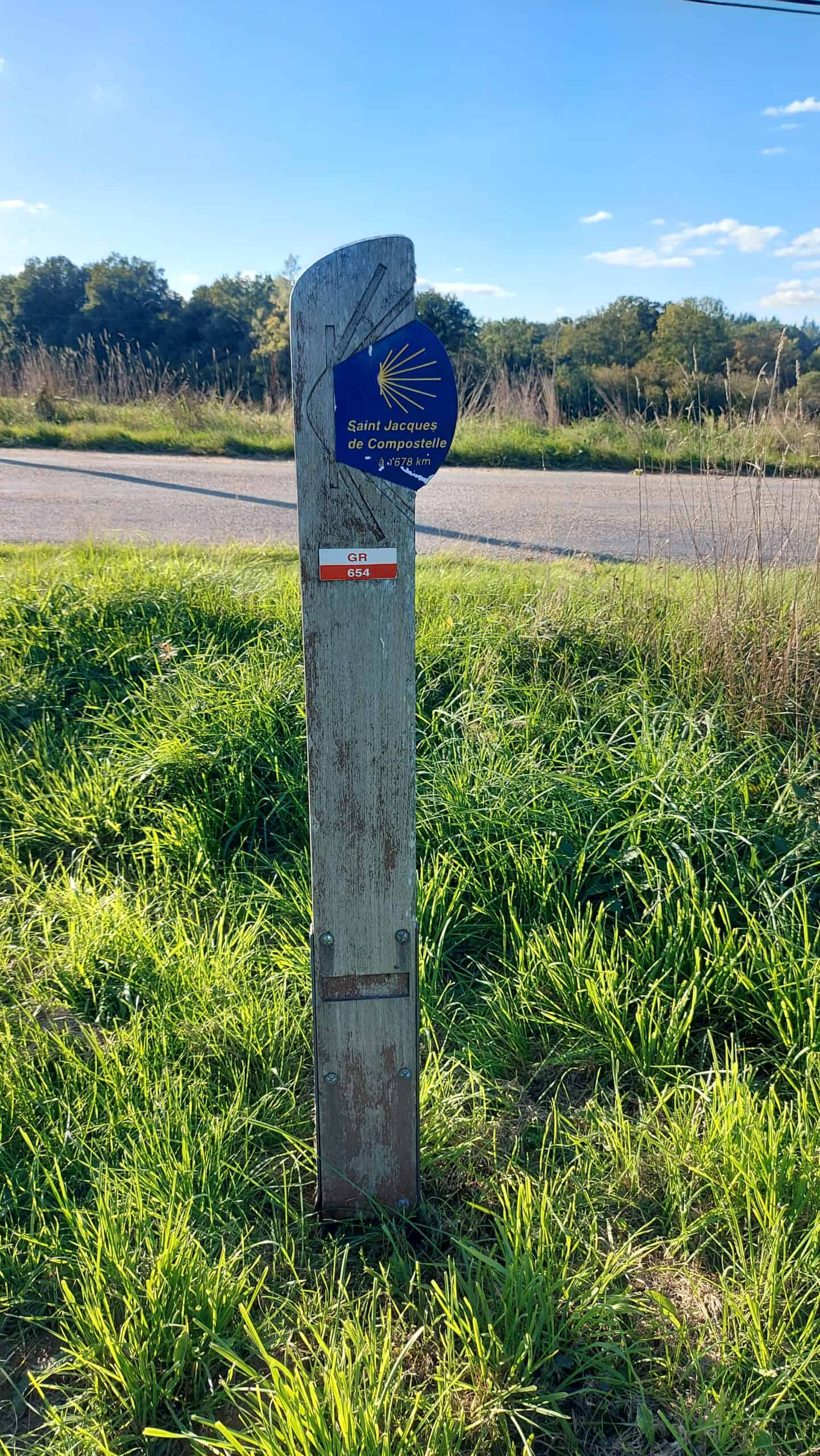 Jakobsmuschel-Wegmarkierung an einem Holzpfosten