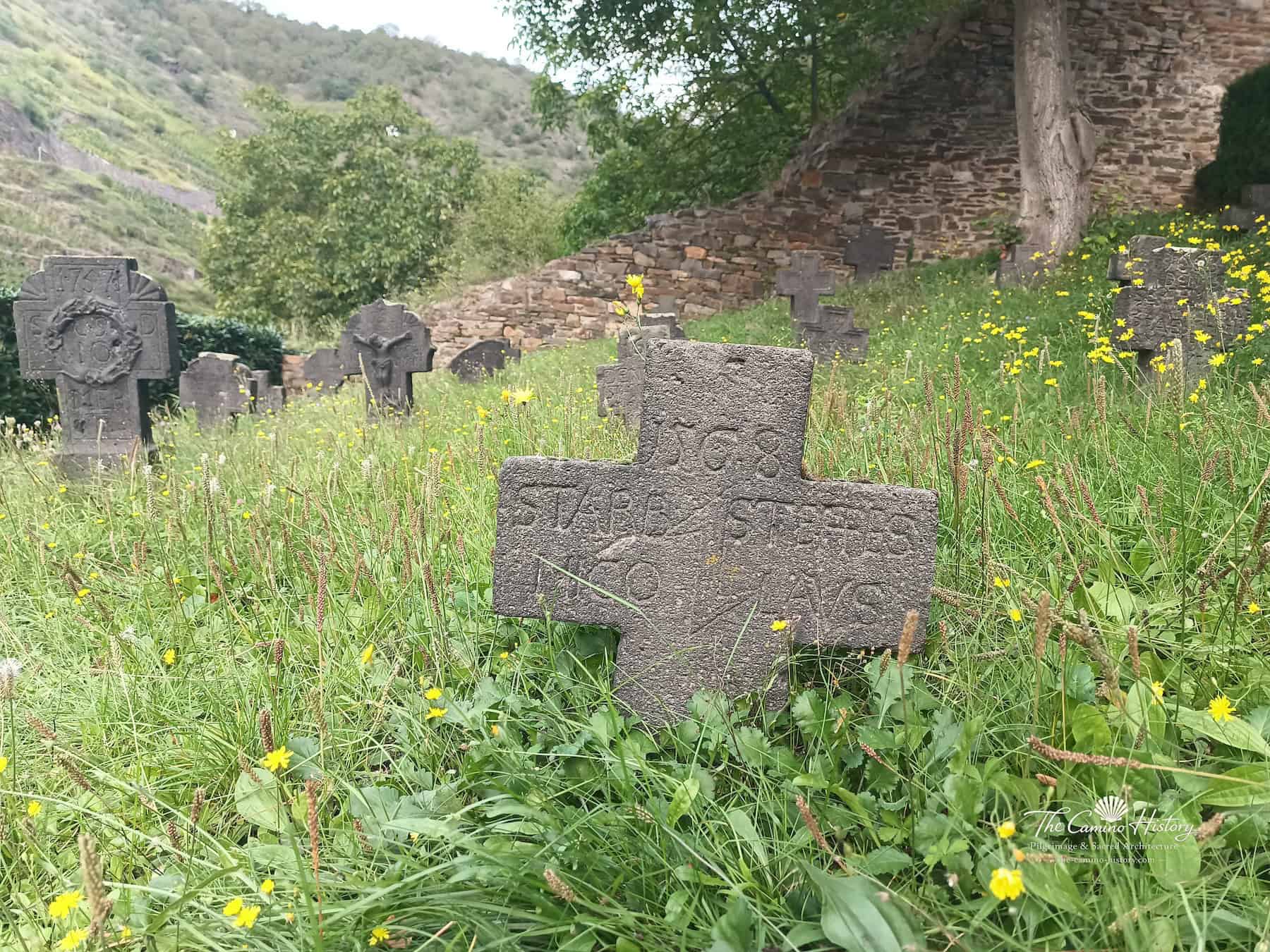 Nahaufnahme eines schlichten, beschrifteten Basaltgrabkreuzes auf dem Kirchhof von Alken