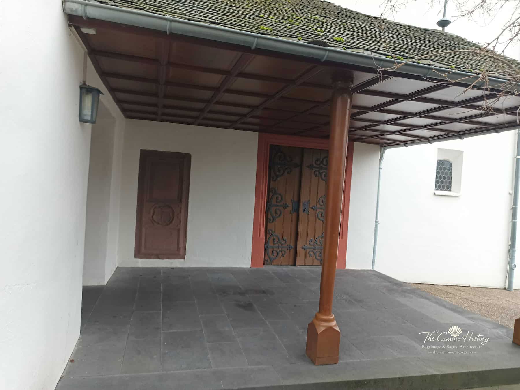 Überdachte Eingangsvorhalle der evangelischen Peterskirche Traben mit Holztüren und eisernen Beschlägen
