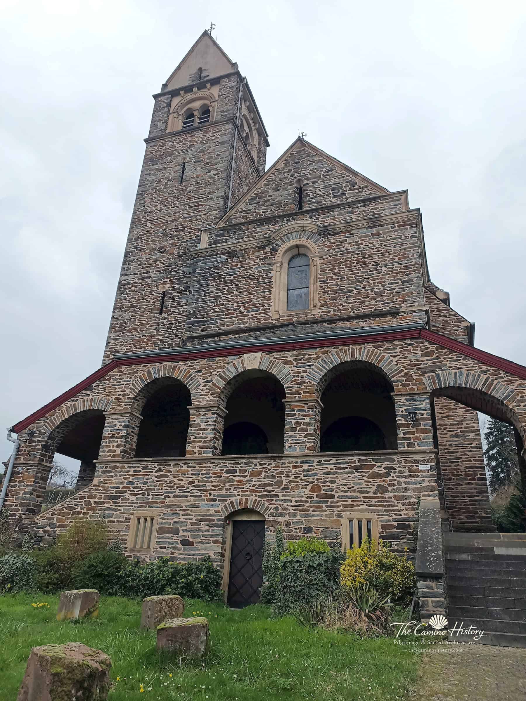 Westfassade der katholischen Kirche St. Peter und Paul in Traben mit hohem Glockenturm, Rundbogenarkaden und Treppe.