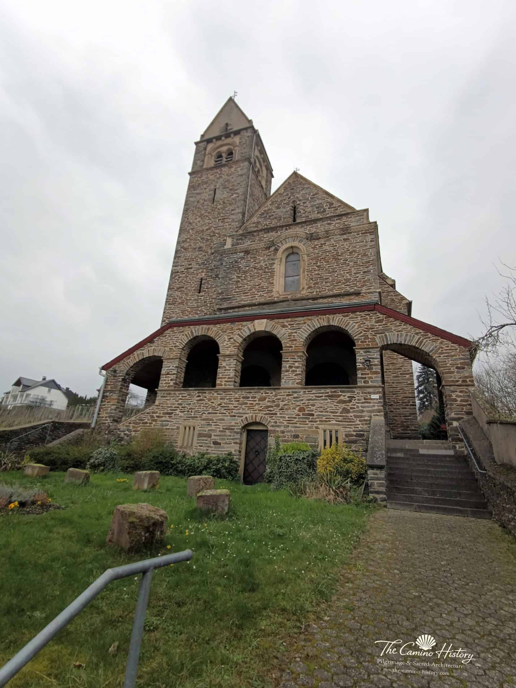 Traben – St. Peter und Paul, Westfassade und Kirchturm über dem Vorplatz mit Sandsteinen des begehbaren Rosenkranzes.