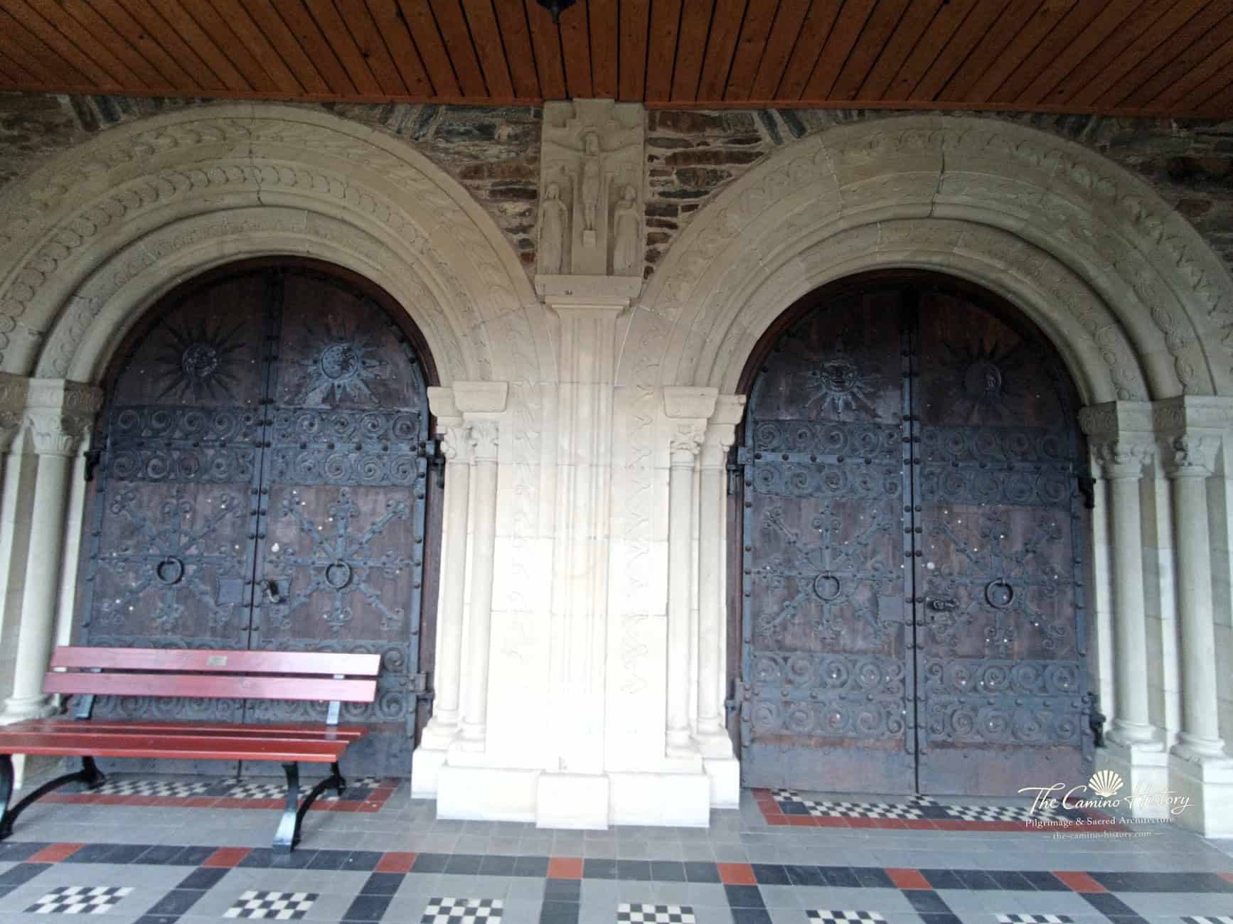 Zwei romanisierende Rundbogenportale von St. Peter und Paul in Traben mit ornamentalen Türbeschlägen und Sitzbank.