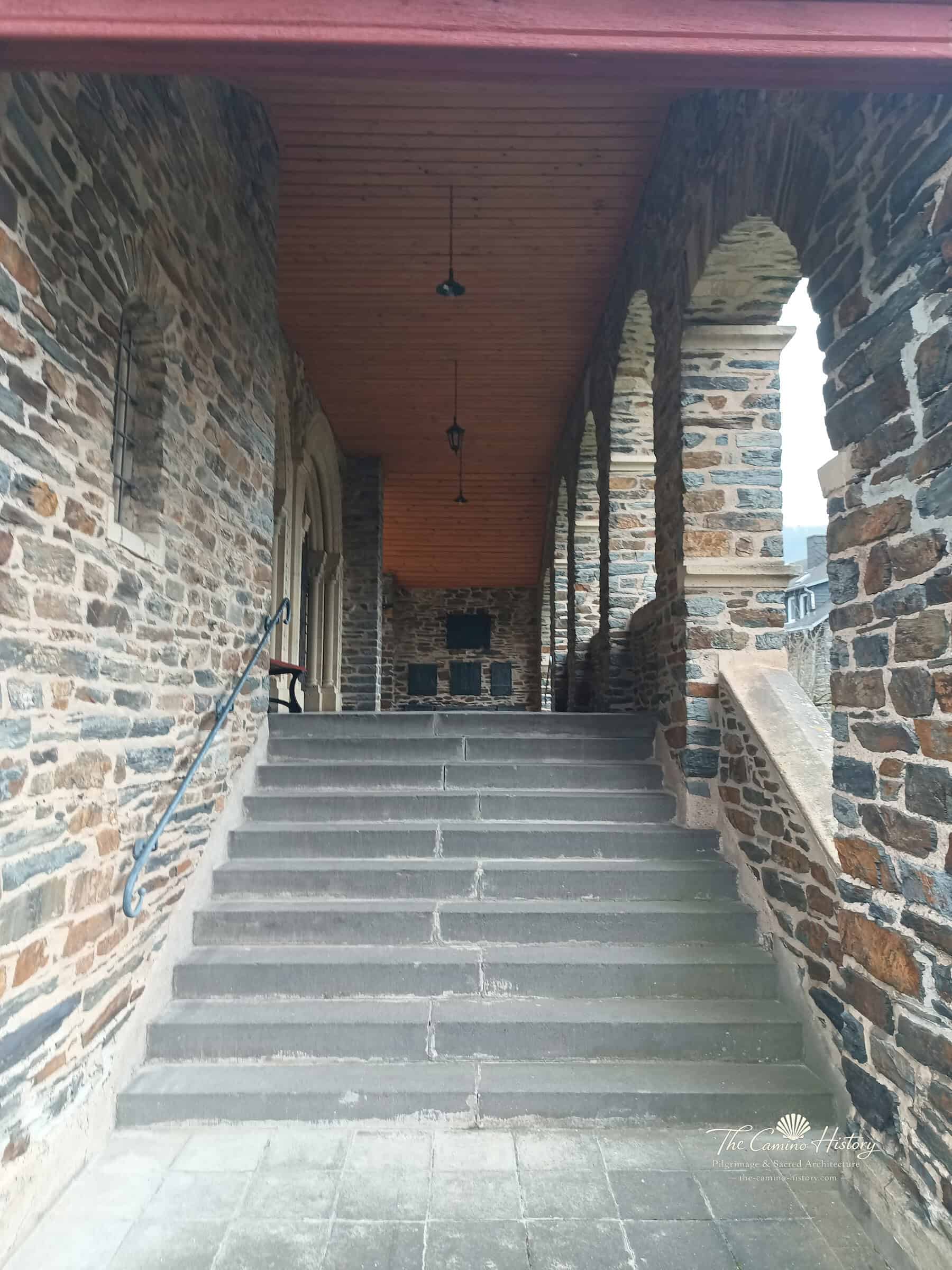 Überdachte steinerne Freitreppe zur Portalvorhalle von St. Peter und Paul in Traben mit Rundbogenarkaden.