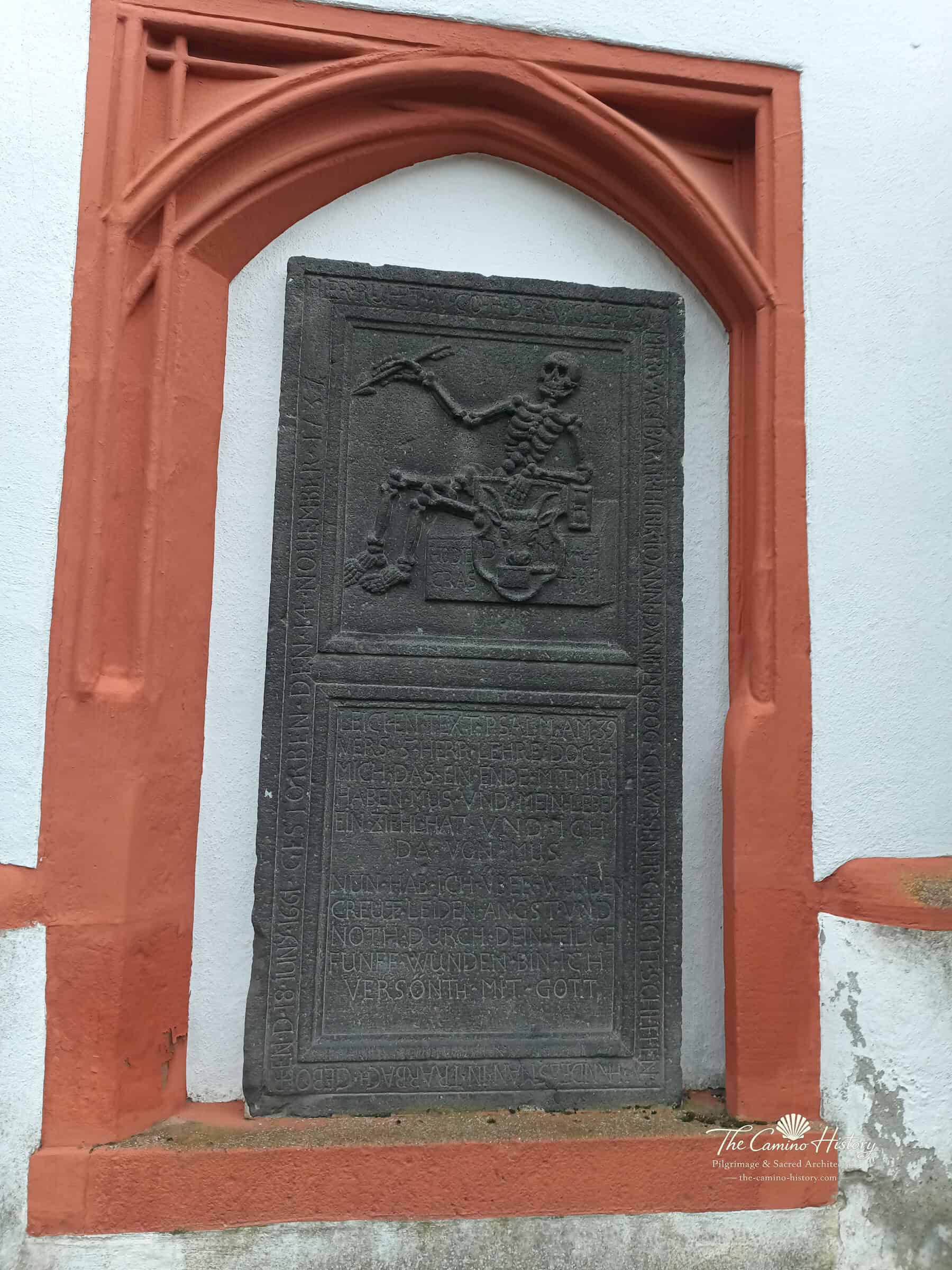 Trarbach – Grabdenkmal mit Skelett und Psalm 39 1 Historisches Grabdenkmal an der evangelischen Kirche Trarbach: schwarze Steinplatte im rot gerahmten Wandfeld mit Skelett, Wappen und Inschriften
