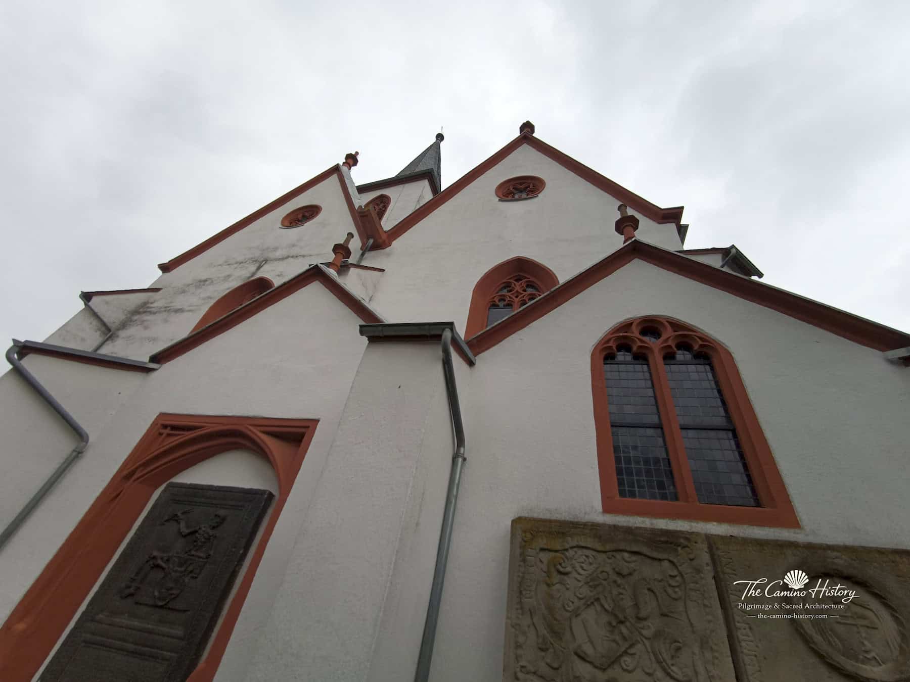 Trarbach – Evangelische Kirche (ehemals St. Nikolaus) 6 Blick nach oben auf die mehrfach gestaffelten Giebel der evangelischen Kirche Trarbach mit historischer Skelettplatte und weiteren Grabsteinen an der Wand