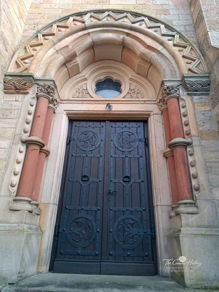 Das kleinere Rundbogenportal von St. Georg mit Säulen, ornamentierter Bogenarchitektur und kleinem Rundfenster.