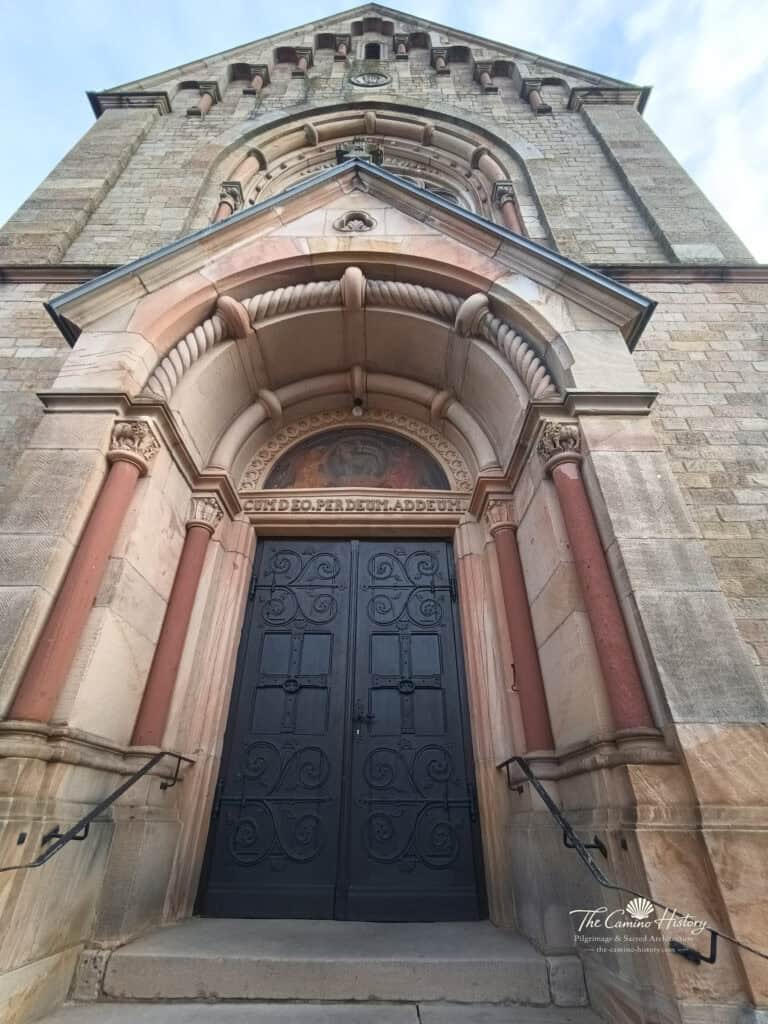 Das monumentale Hauptportal von St. Georg mit kräftigen Rundbögen, Säulen und historistischer Sandsteinarchitektur.