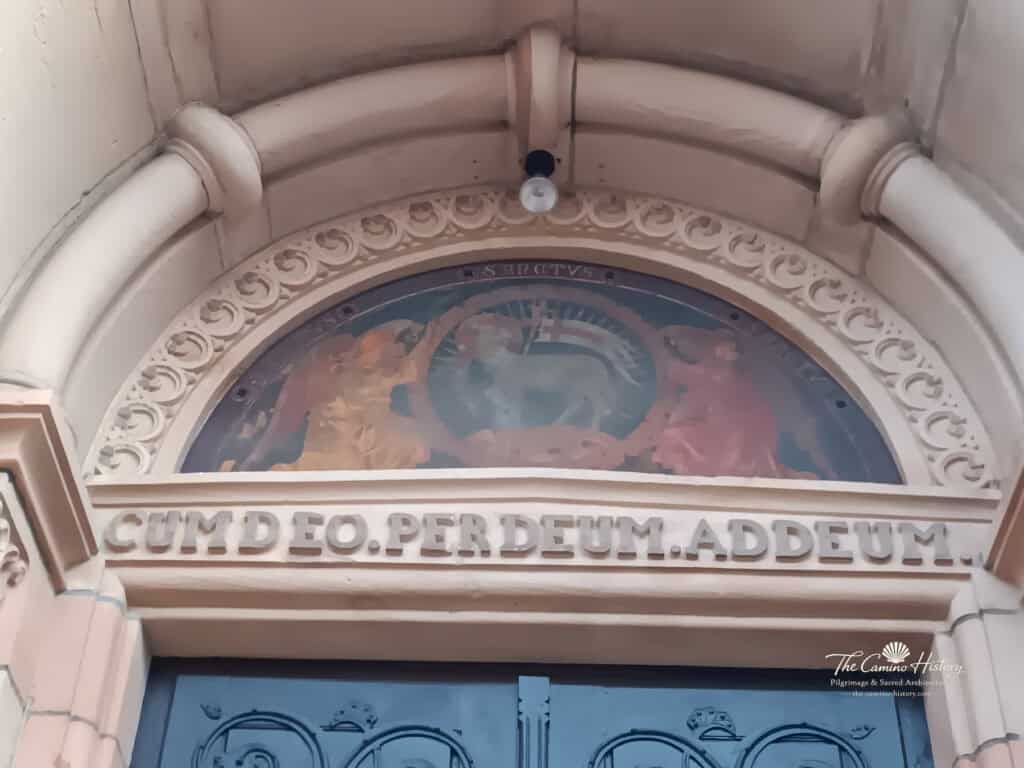Die Inschrift „Cum Deo – per Deum – ad Deum“ über dem Hauptportal von St. Georg.