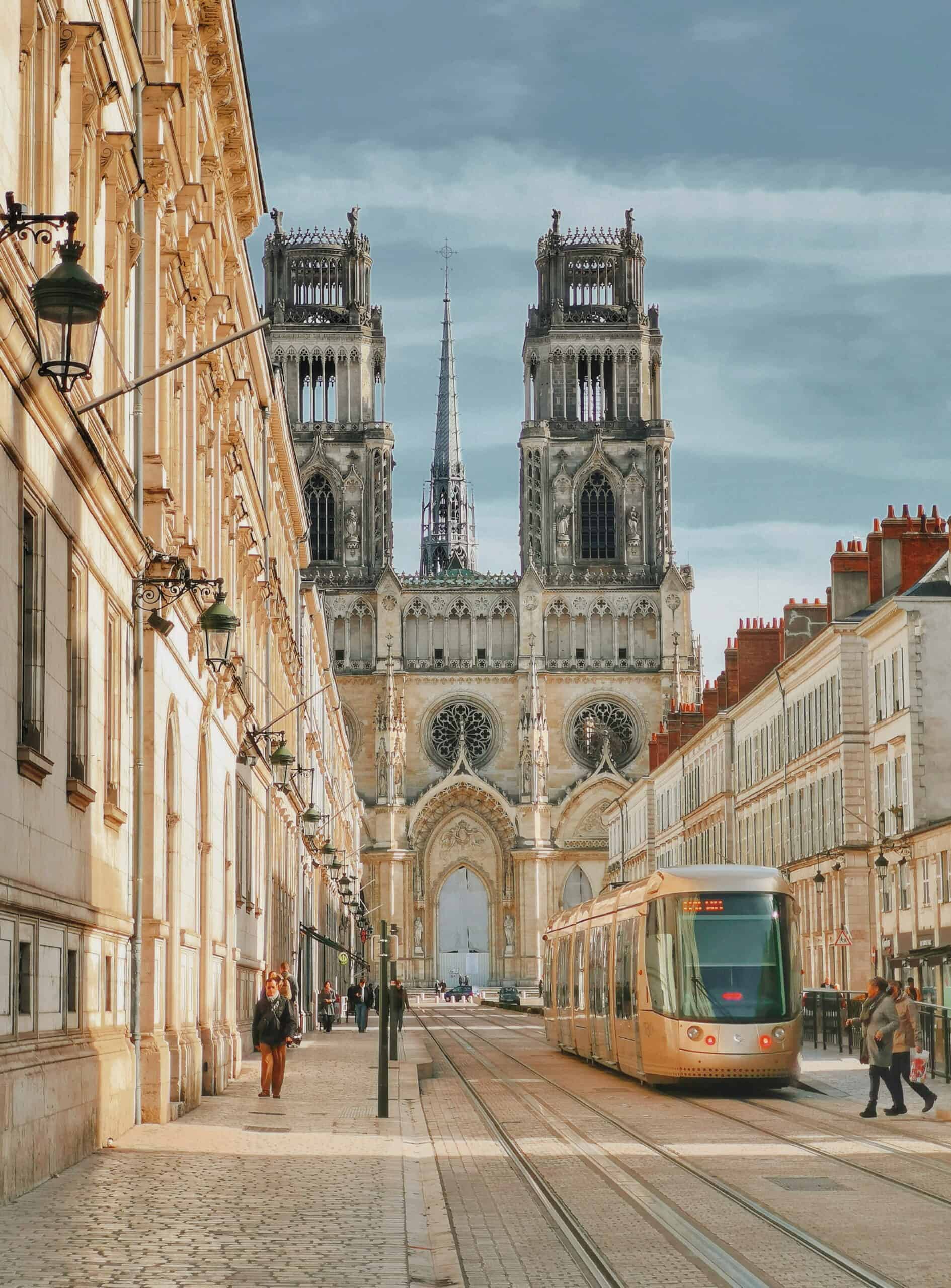 via turonensis 2 Blick durch eine Straße in Orléans auf die gotische Kathedrale Sainte-Croix und eine Straßenbahn