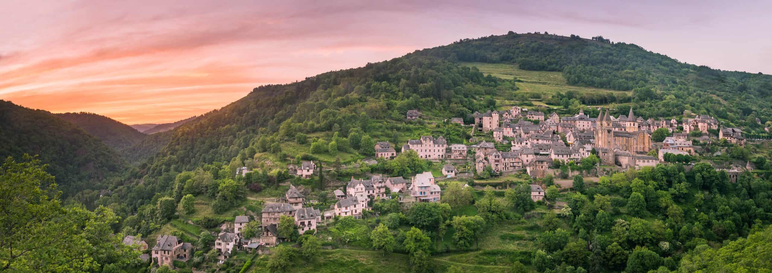 Panoramablick auf die mittelalterliche Ortschaft Conques bei Sonnenuntergang